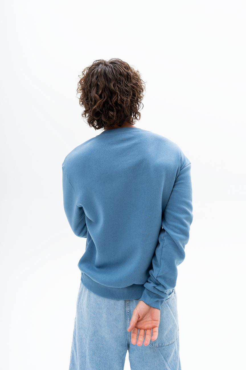 Model wearing AKANTARA Basic Crewneck Sweatshirt in blue, styled with casual streetwear